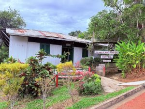 Panorámica exterior del Hotel Lomas del Paiyú. La imagen destaca la arquitectura rústica regional, el letrero principal del hotel y la exuberante vegetación del jardín frontal bajo un cielo nublado.