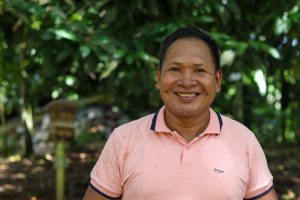 Retrato del guía local Wainer de Puerto Nariño, Amazonas. Su sonrisa genuina refleja la amabilidad y el espíritu comunitario de la región. La luz natural y el fondo selvático subrayan la conexión armónica de las personas con su entorno natural.